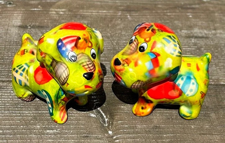 Twee keramieken hondjes van Pomme Pidou in groen 'Air Balloons Gardengreen'-design, als vrolijk peper- en zoutstel op een tafel.