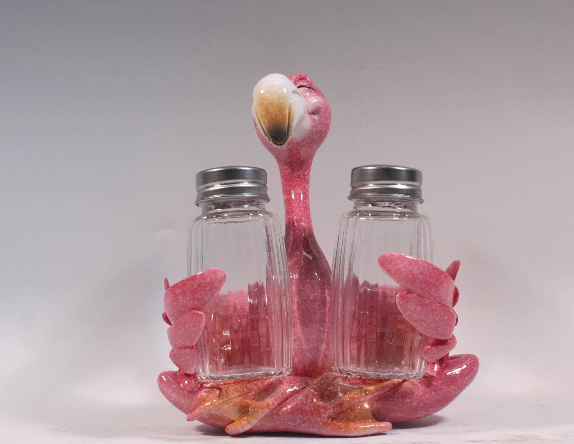 Tropisch peper- en zoutstel met roze flamingo die twee glazen kruidenpotjes omarmt, ca. 13x15 cm